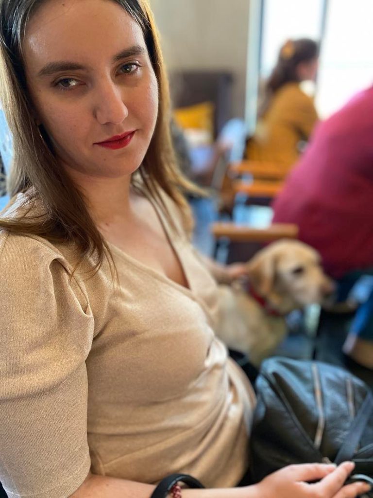 Φωτογραφία από προηγούμενο meetup του IDEADECO. Η Χριστίνα Σαρρή, περιποιημένη, κάθεται σε καρέκλα. Πίσω της φαίνεται η Λούνα.