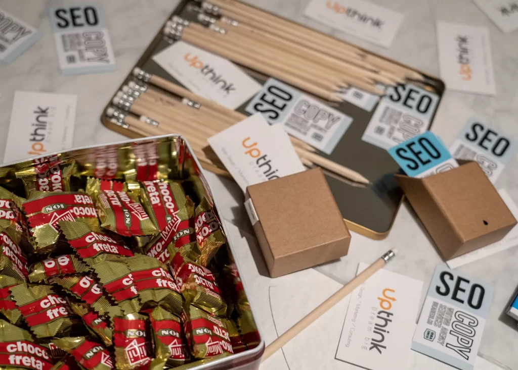 Κεντρικό τραπέζι σαλονιού. Πάνω του έχει σημειωματάρια με αυτοκόλητα από το meetup, ξύλινα μολύβια, κάρτες επαγγελματικές, μεταλλικό κουτί με μικρά σοκοφρετάκια.