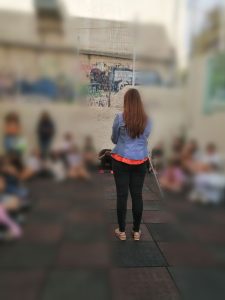 Η Χριστίνα Σαρρή είναι όρθια και δείχνει με το κινητό της. Στα δεξιά της βρίσκεται το μπαστούνι της