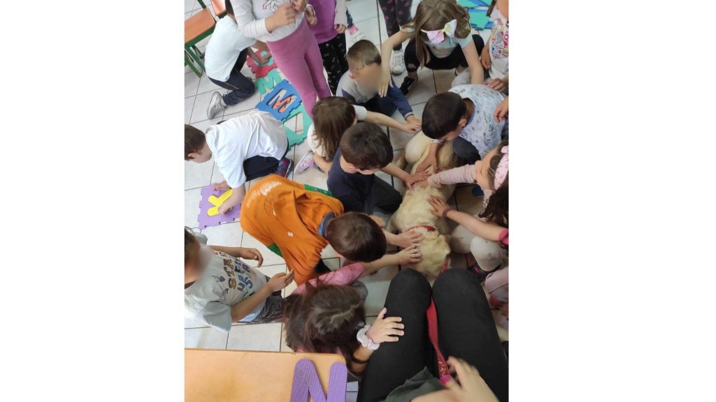 Η Χριστίνα Σαρρή σε σχολείο περιτριγυρισμένη από παιδιά που χαϊδεύουν τη Λούνα στο τέλος της ομιλίας.